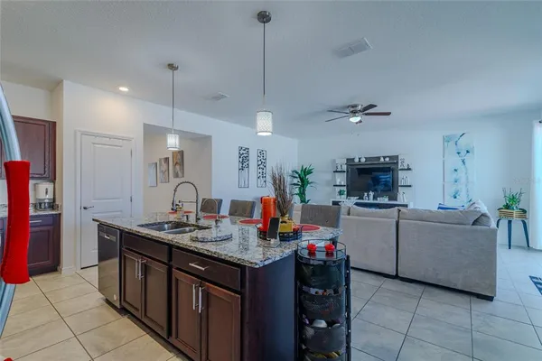 a kitchen with stainless steel appliances granite countertop a stove top oven a refrigerator a sink dishwasher a dining table and chairs with wooden floor