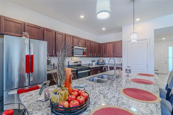 a kitchen with kitchen island stainless steel appliances granite countertop a sink and a refrigerator