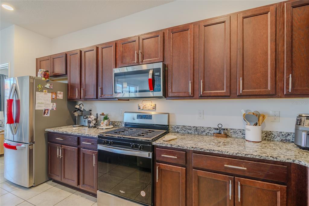 7095 Southwest 61st Place Ocala, FL 34474 - Photo 20 of 61 a kitchen with stainless steel appliances granite countertop a stove a sink dishwasher and cabinets with wooden floor
