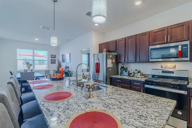 a kitchen with kitchen island stainless steel appliances granite countertop a sink and a refrigerator
