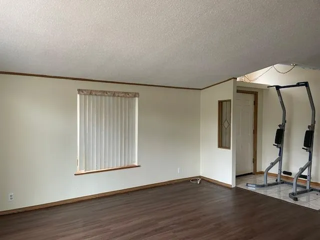 a view of an empty room with wooden floor and a cabinet