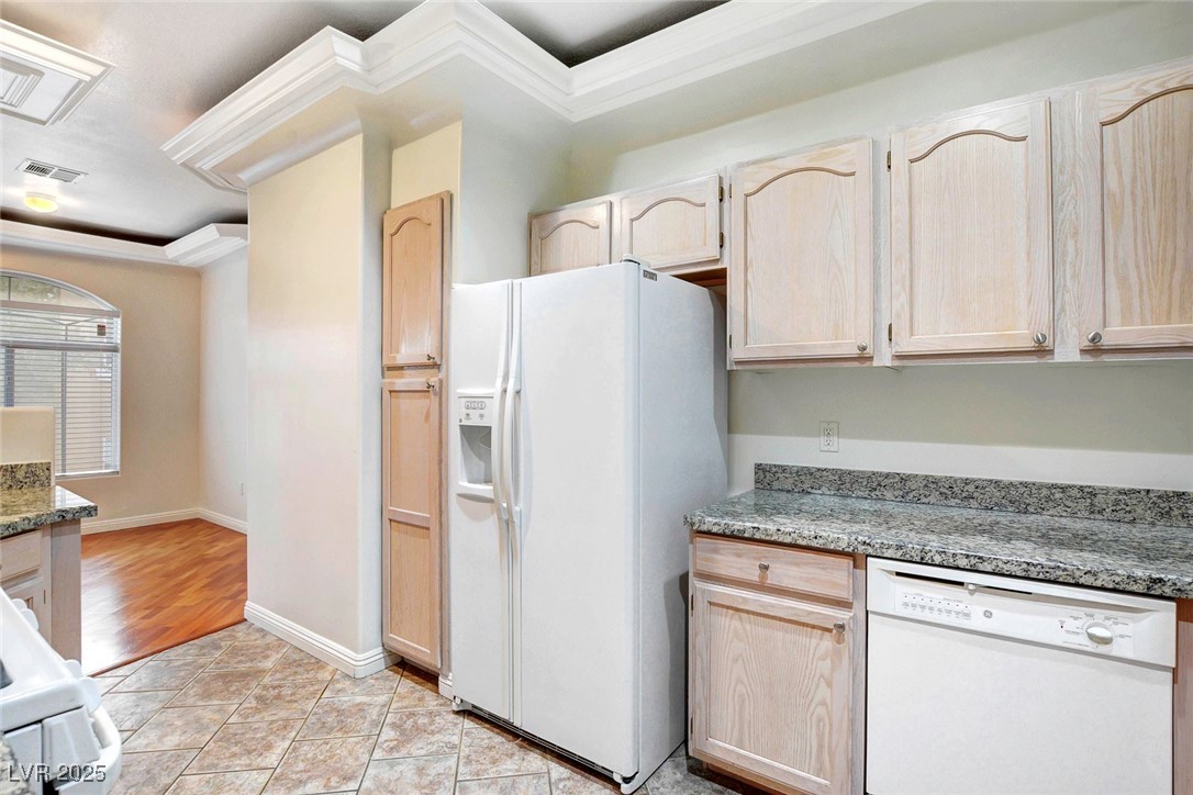 8725 Red Rio Drive, Unit 203 Las Vegas, NV 89128 - Photo 11 of 38 Kitchen with white appliances, light brown cabinetry, crown molding, and light stone counters