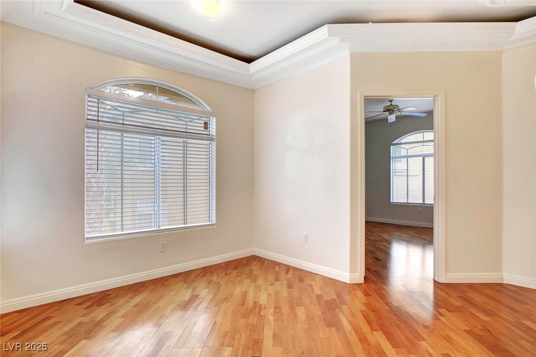 8725 Red Rio Drive, Unit 203 Las Vegas, NV 89128 - Photo 13 of 38 Empty room featuring light wood-style floors, baseboards, ornamental molding, and a tray ceiling