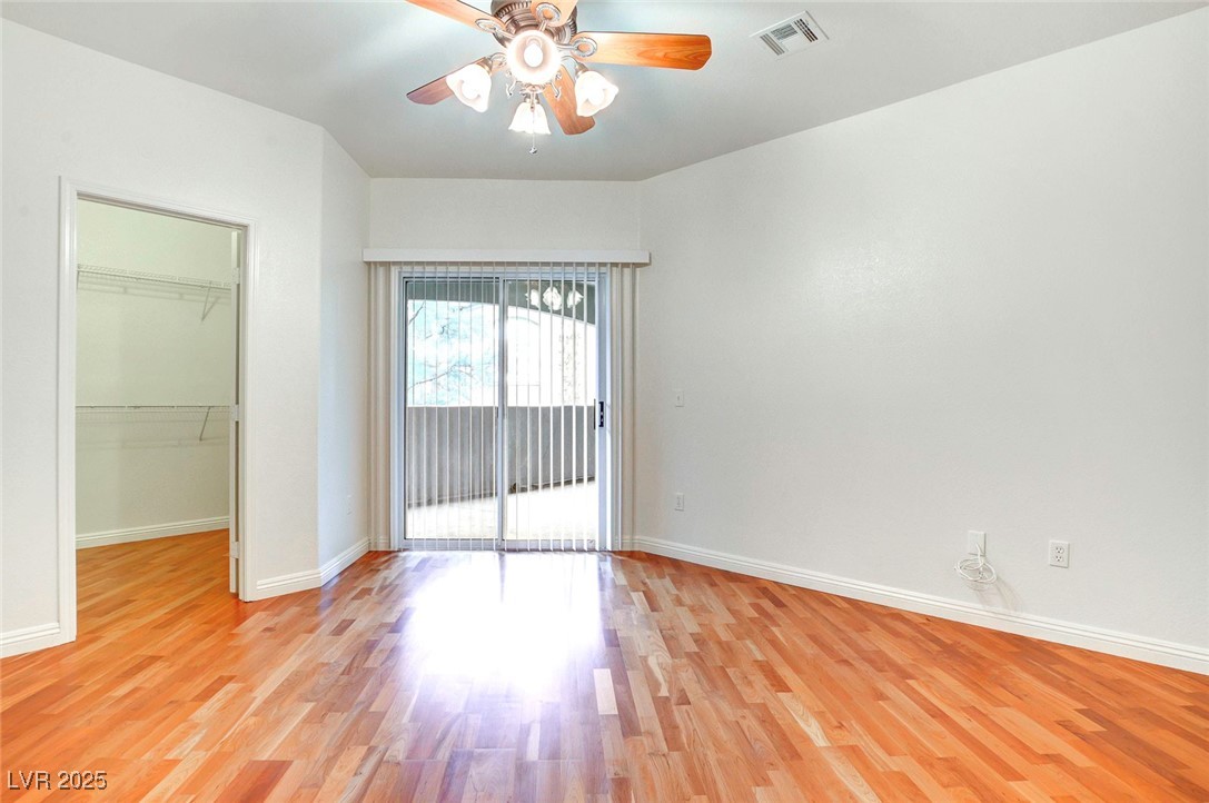 8725 Red Rio Drive, Unit 203 Las Vegas, NV 89128 - Photo 25 of 38 Unfurnished bedroom featuring a spacious closet, light wood finished floors, access to outside, baseboards, and a closet