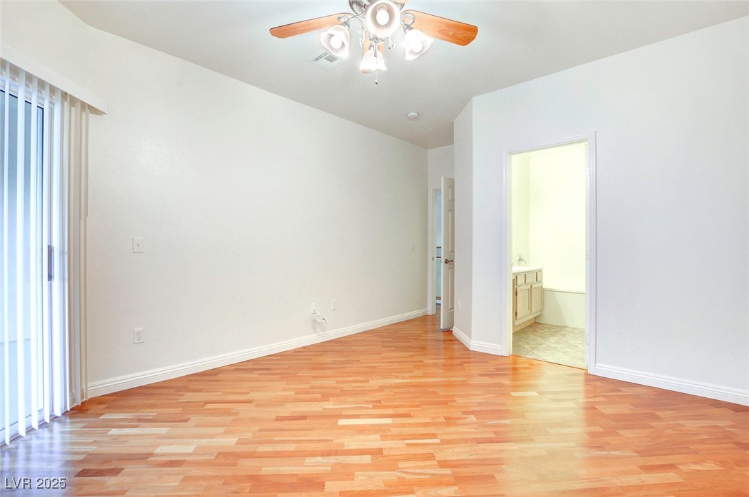 8725 Red Rio Drive, Unit 203 Las Vegas, NV 89128 - Photo 26 of 38 Unfurnished bedroom with light wood-style floors, vaulted ceiling, baseboards, and connected bathroom