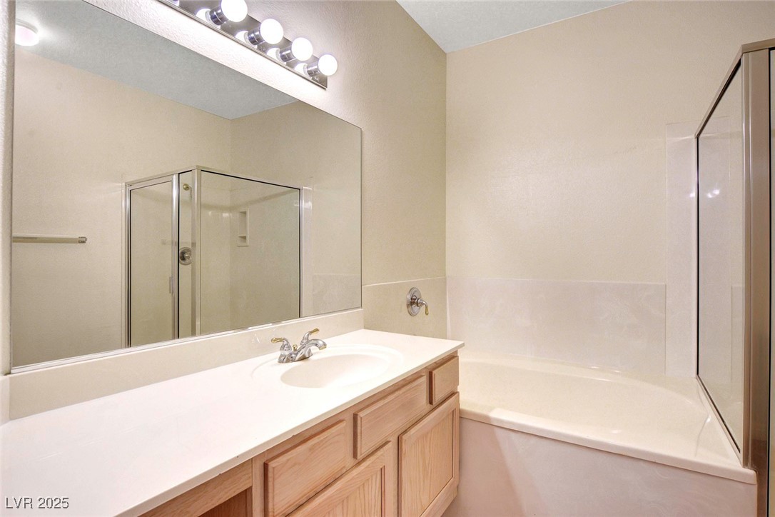8725 Red Rio Drive, Unit 203 Las Vegas, NV 89128 - Photo 28 of 38 Full bathroom featuring a bath, a shower stall, and vanity