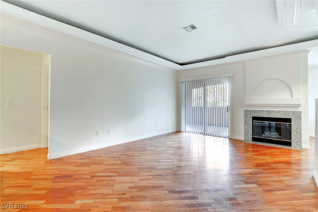 8725 Red Rio Drive, Unit 203 Las Vegas, NV 89128 - Photo 3 of 38 Unfurnished living room with baseboards, light wood finished floors, and a fireplace