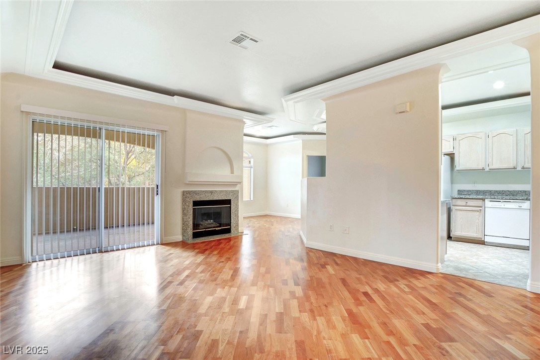 8725 Red Rio Drive, Unit 203 Las Vegas, NV 89128 - Photo 4 of 38 Unfurnished living room with light wood-type flooring, baseboards, crown molding, a fireplace with flush hearth, and recessed lighting