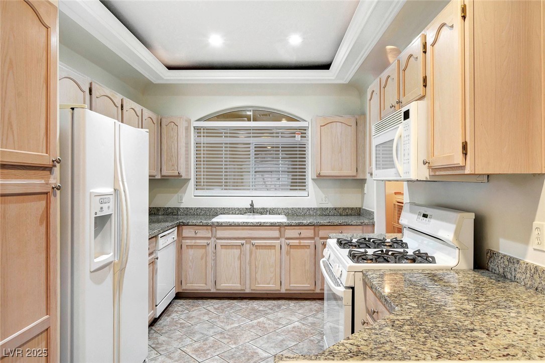8725 Red Rio Drive, Unit 203 Las Vegas, NV 89128 - Photo 7 of 38 Kitchen featuring white appliances, light brown cabinets, a sink, a raised ceiling, and ornamental molding