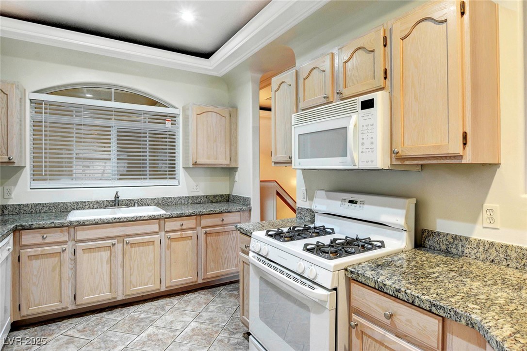 8725 Red Rio Drive, Unit 203 Las Vegas, NV 89128 - Photo 8 of 38 Kitchen featuring white appliances, light brown cabinets, a sink, and ornamental molding