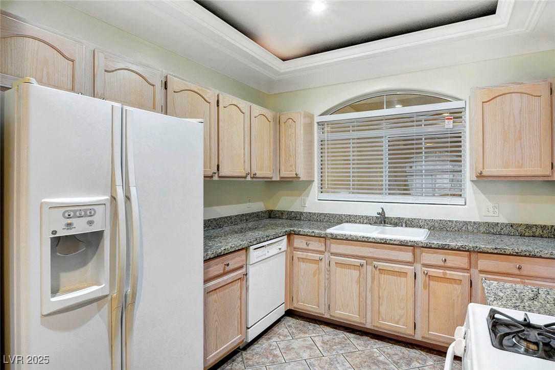 8725 Red Rio Drive, Unit 203 Las Vegas, NV 89128 - Photo 9 of 38 Kitchen featuring white appliances, light brown cabinets, a sink, a raised ceiling, and light tile patterned floors