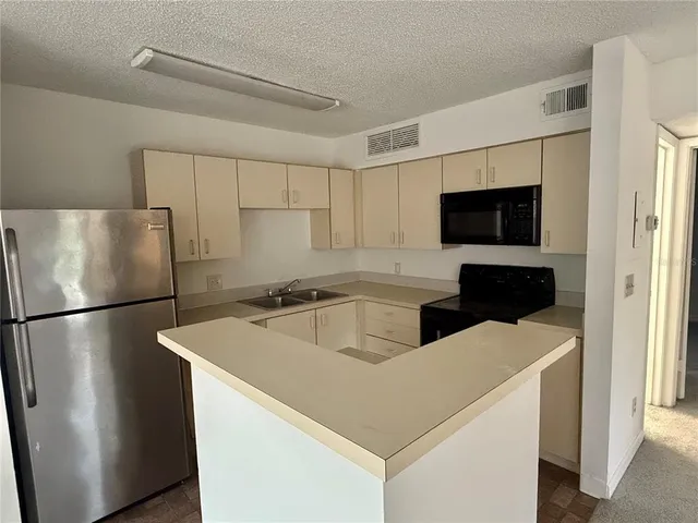a view of kitchen with furniture a refrigerator and a stove top oven