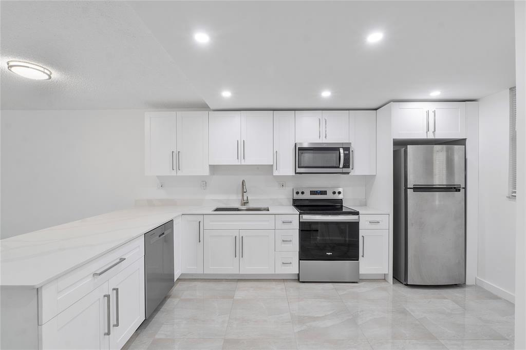 a large kitchen with stainless steel appliances granite countertop a stove a sink and a refrigerator