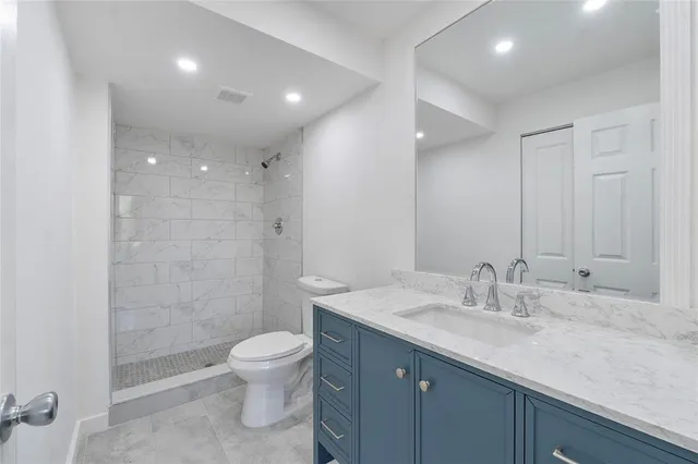 a bathroom with a granite countertop sink a toilet and shower