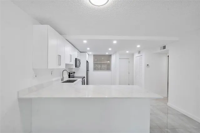 a large white kitchen with a lot of counter space and a sink