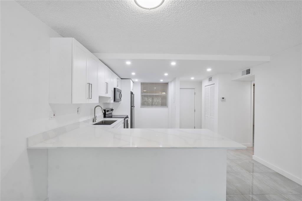 3751 Environ Boulevard, Unit 243 Lauderhill, FL 33319 - Photo 3 of 24 a large white kitchen with a lot of counter space and a sink