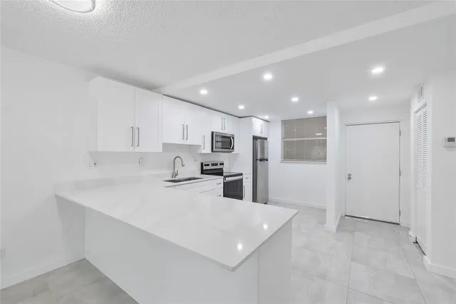 a kitchen with stainless steel appliances kitchen island sink refrigerator and cabinets