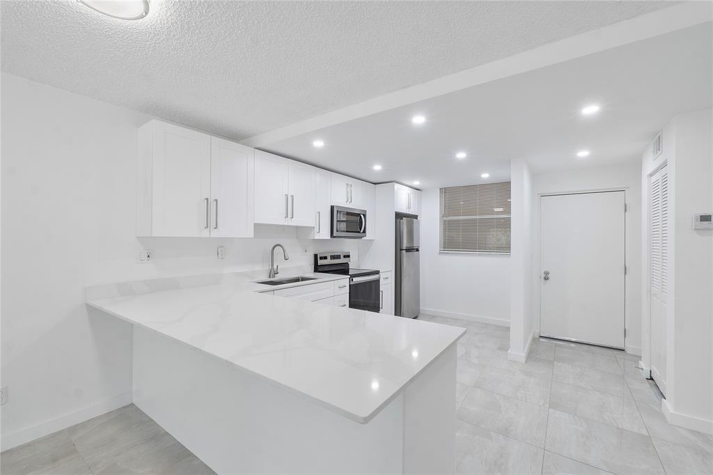 3751 Environ Boulevard, Unit 243 Lauderhill, FL 33319 - Photo 4 of 24 a kitchen with stainless steel appliances kitchen island sink refrigerator and cabinets