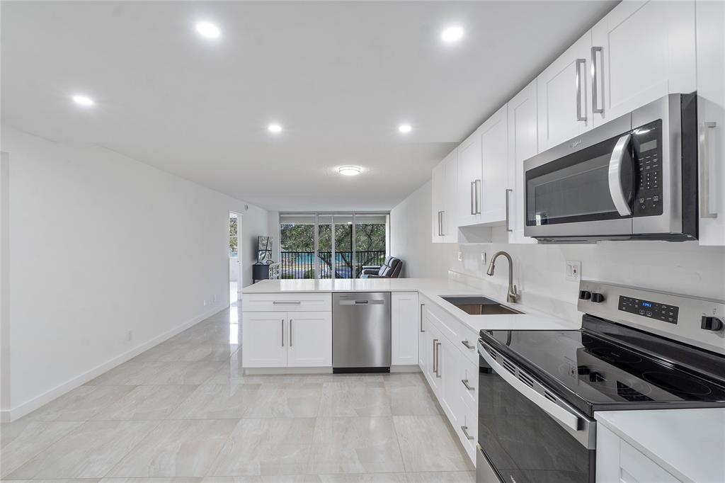 3751 Environ Boulevard, Unit 243 Lauderhill, FL 33319 - Photo 5 of 24 a kitchen with stainless steel appliances granite countertop a stove top oven a sink dishwasher and white cabinets with wooden floor