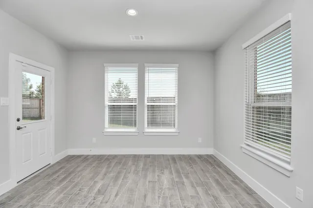an empty room with windows and ceiling fan