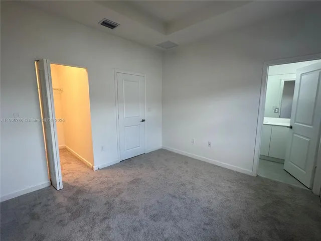 an empty room with a window and a kitchen view