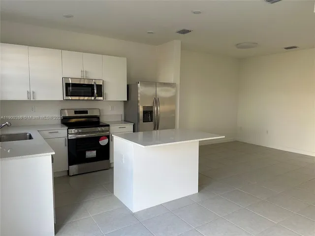 a kitchen with kitchen island a sink a stove and refrigerator