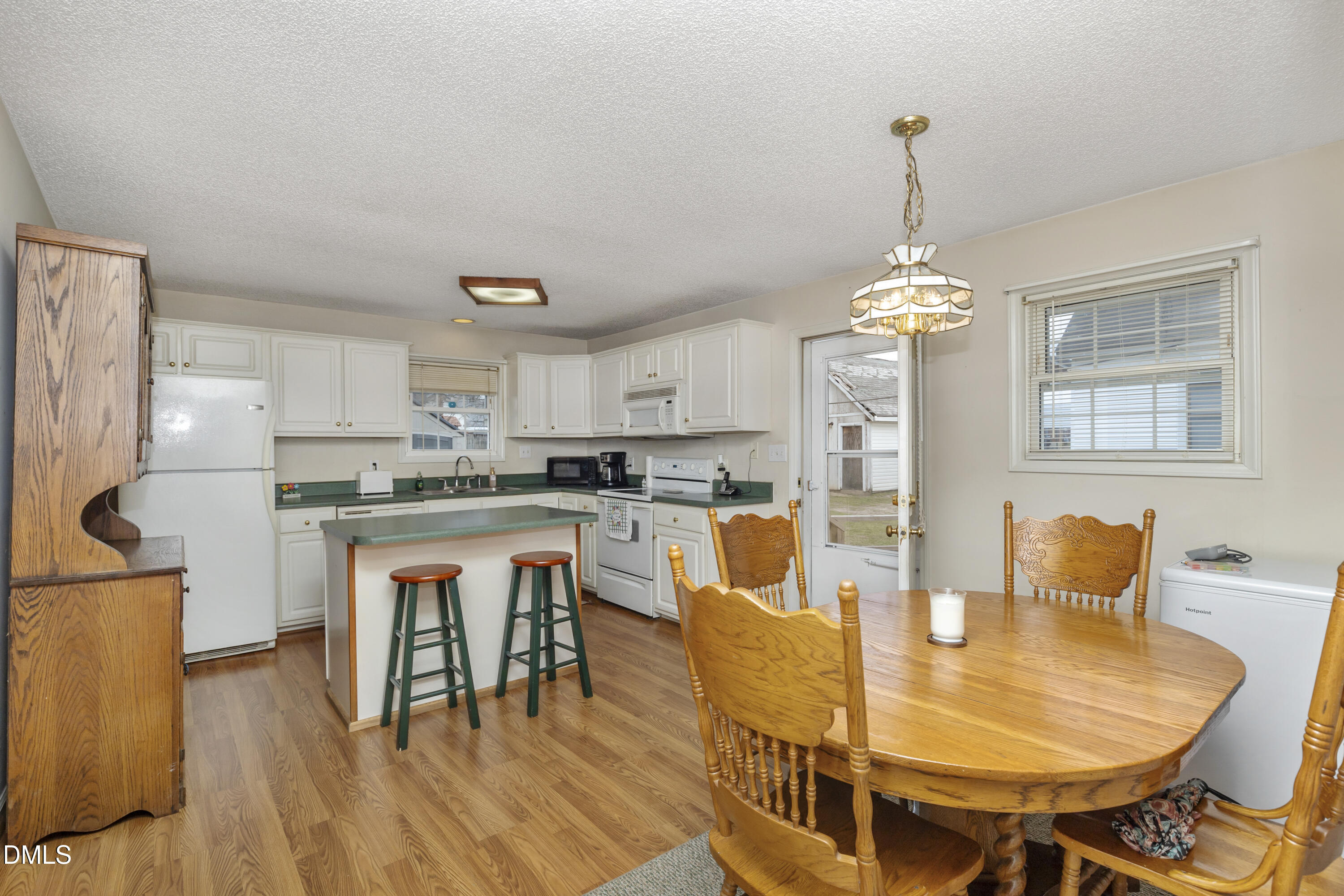 100 East E Street Erwin, NC 28339 - Photo 17 of 27 a dining room with stainless steel appliances kitchen island granite countertop a dining table chairs and a refrigerator a mirror with wooden floors