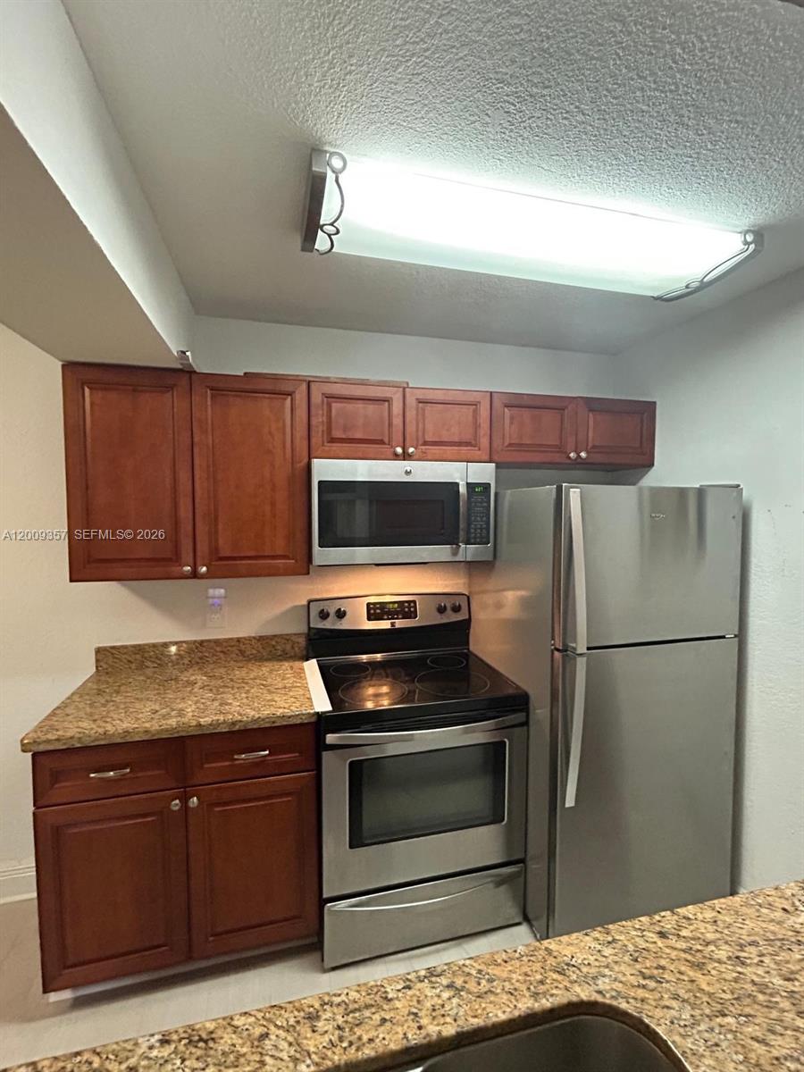 15551 Southwest 104th Terrace, Unit 814 Miami, FL 33196 - Photo 11 of 30 a kitchen with granite countertop stainless steel appliances and wooden cabinets