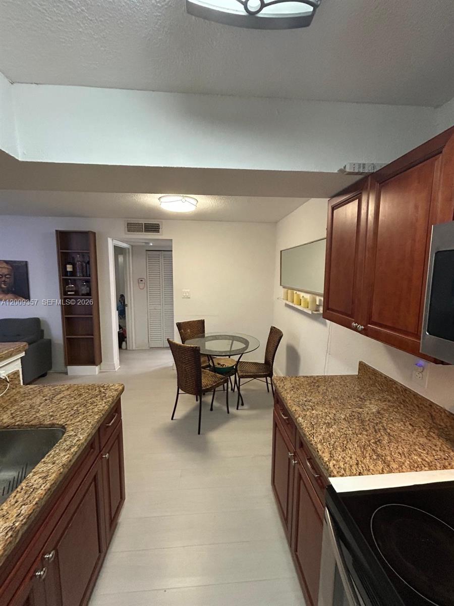 15551 Southwest 104th Terrace, Unit 814 Miami, FL 33196 - Photo 12 of 30 a kitchen with kitchen island granite countertop wooden cabinets and stainless steel appliances