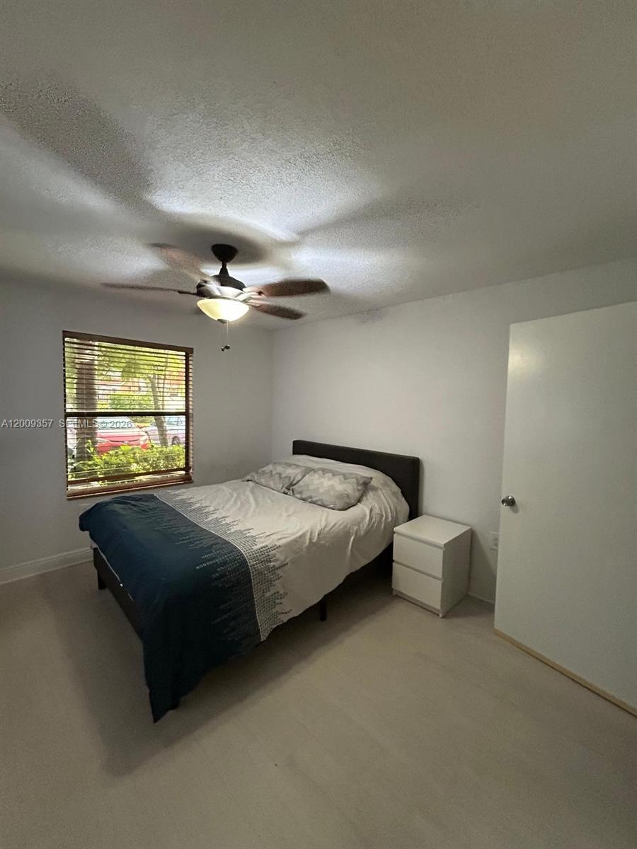 15551 Southwest 104th Terrace, Unit 814 Miami, FL 33196 - Photo 15 of 30 a spacious bedroom with a bed and a chandelier