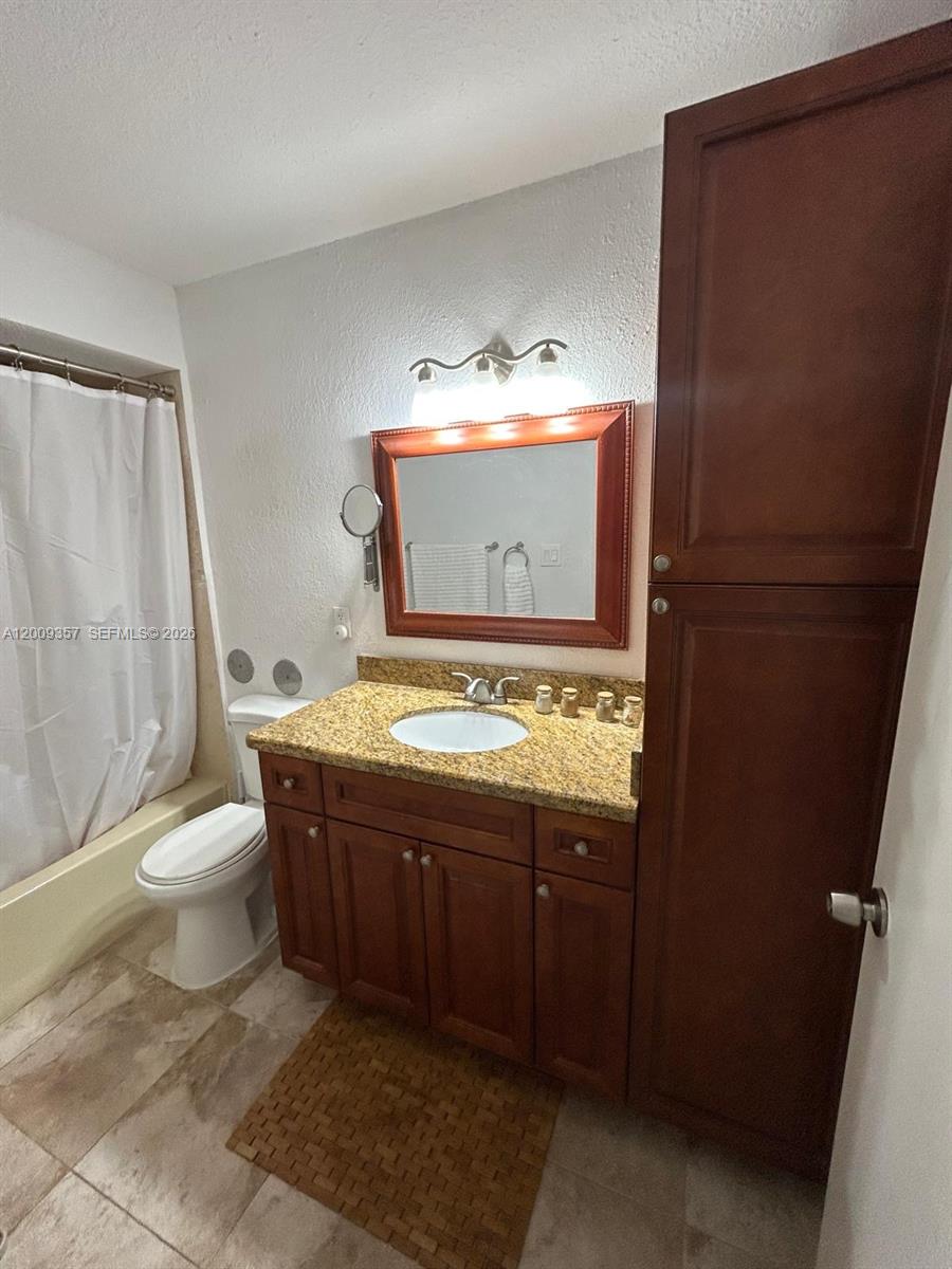 15551 Southwest 104th Terrace, Unit 814 Miami, FL 33196 - Photo 19 of 30 a bathroom with a granite countertop toilet sink and mirror