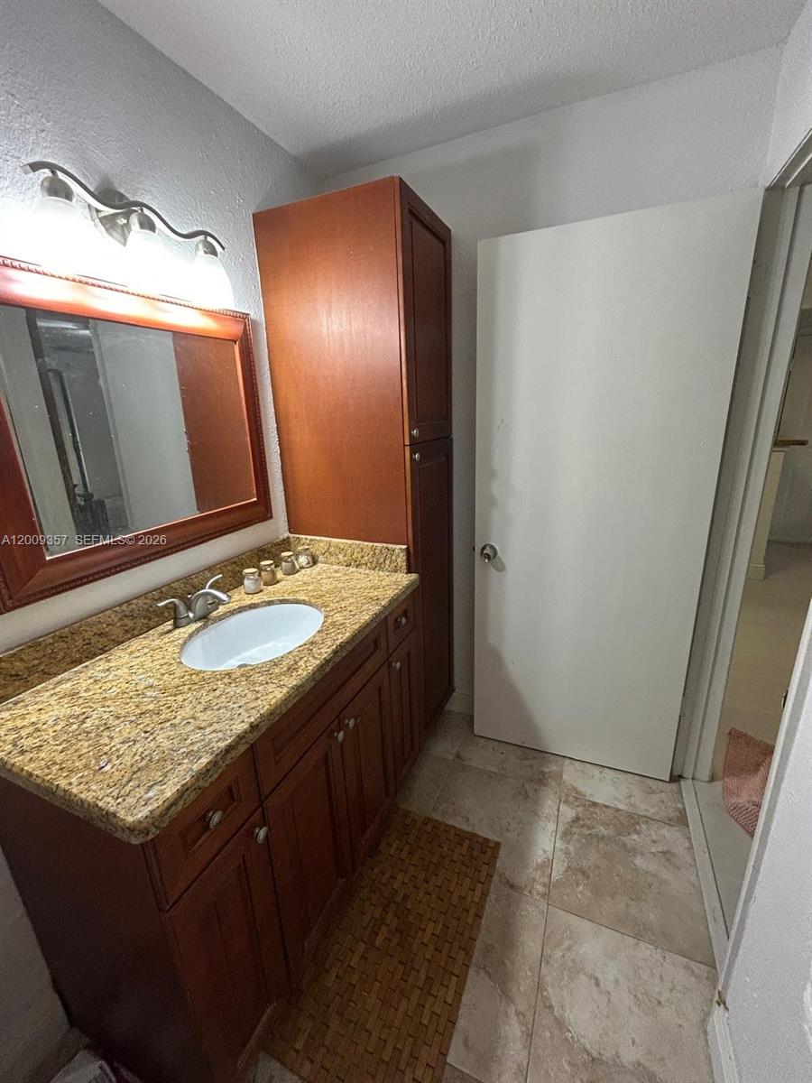 15551 Southwest 104th Terrace, Unit 814 Miami, FL 33196 - Photo 20 of 30 a bathroom with a granite countertop sink and a mirror