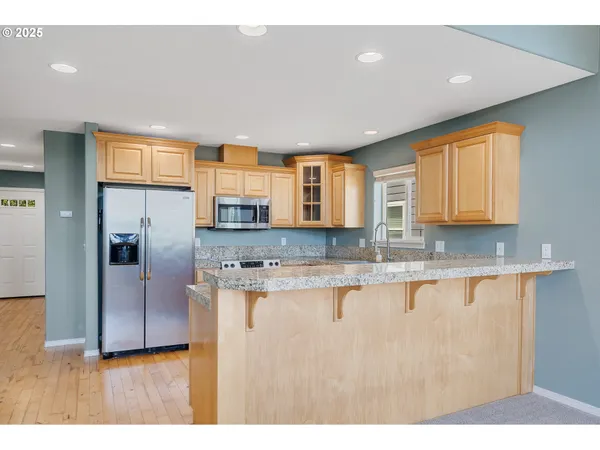 a kitchen with stainless steel appliances granite countertop a sink a stove and a refrigerator