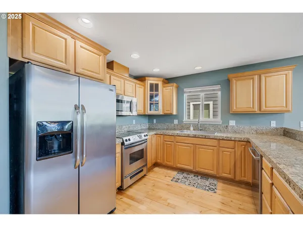 a kitchen with stainless steel appliances granite countertop a sink a stove and refrigerator