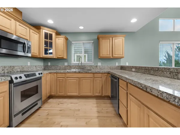a kitchen with stainless steel appliances granite countertop a refrigerator a sink a stove and oven