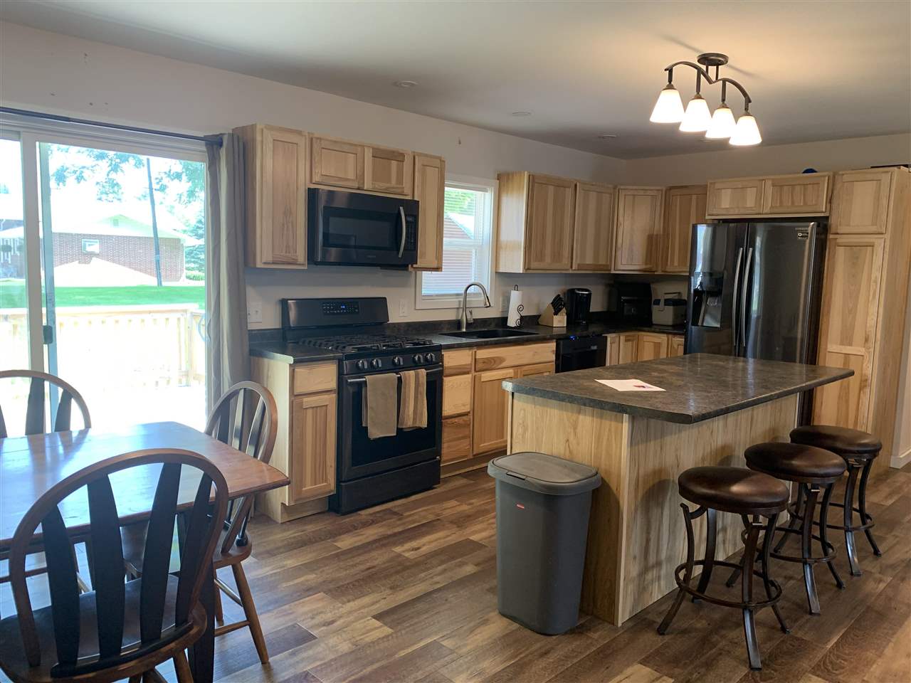 506 Ridge Street Mount Carroll, IL 61053 - Photo 2 of 17 a kitchen with stainless steel appliances granite countertop a stove a refrigerator a sink a dining table and chairs with wooden floor