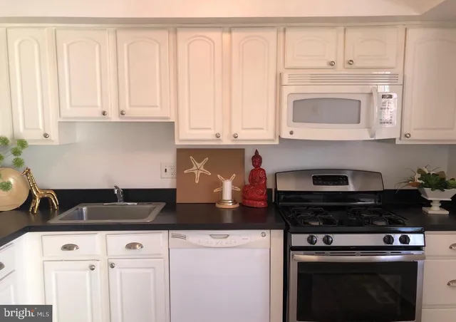 a kitchen with granite countertop white cabinets and black appliances