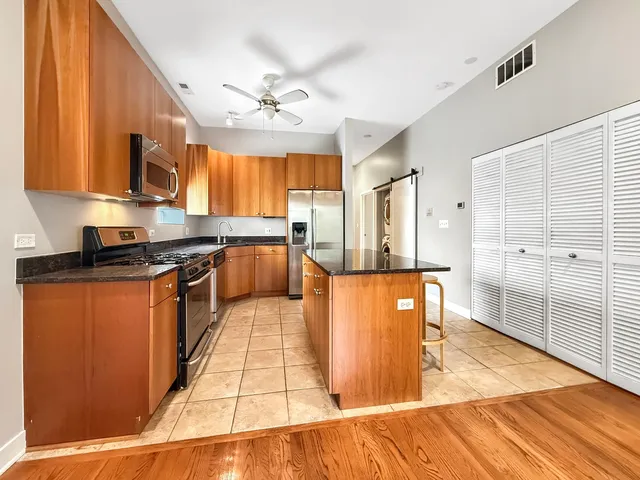 a large kitchen with stainless steel appliances granite countertop plenty wooden cabinets counter space and a window