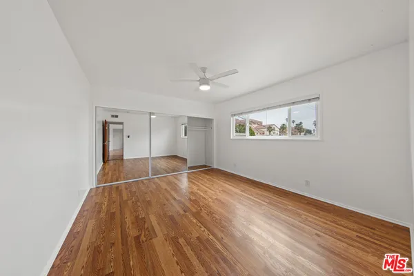 a view of empty room with wooden floor and fan