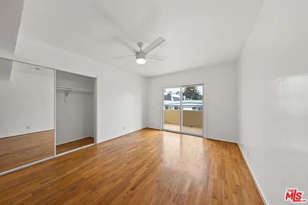 a view of a kitchen with wooden floor a ceiling fan and a window