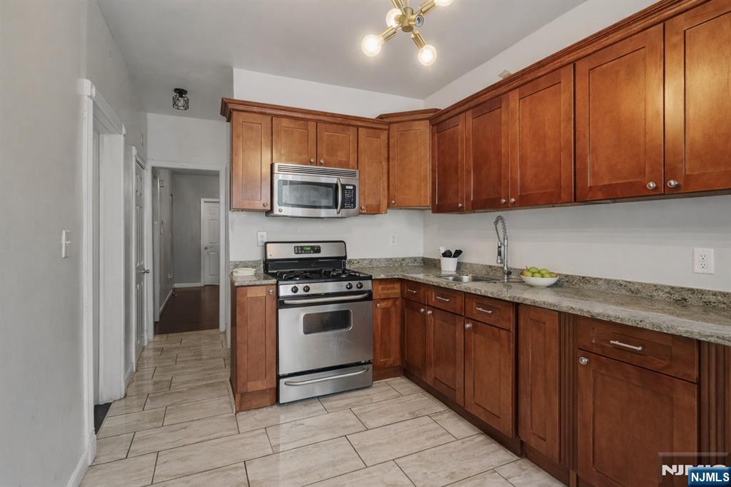 155 Myrtle Avenue Irvington, NJ 07111 - Photo 7 of 26 a kitchen with stainless steel appliances granite countertop a stove top oven a sink dishwasher and a refrigerator with wooden cabinets