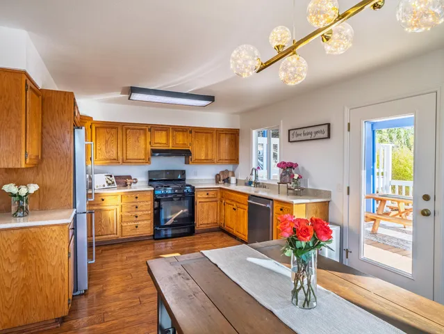 a kitchen with refrigerator a stove and wooden floor