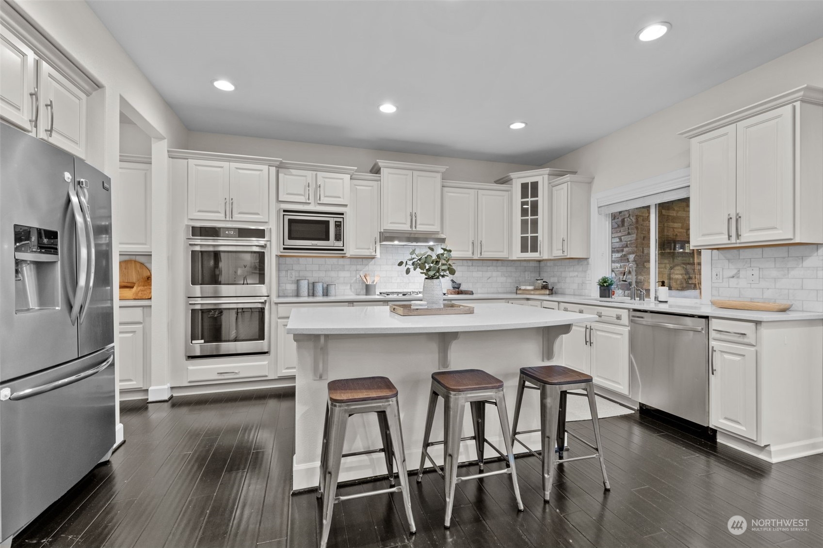 4123 175th Place Southeast Bothell, WA 98012 - Photo 7 of 40 a kitchen with stainless steel appliances granite countertop a stove top oven a sink a refrigerator with white cabinets and wooden floor