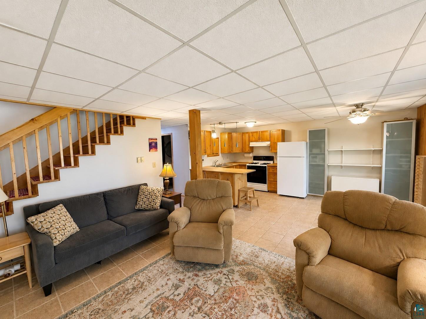 1787 North Bay Road Ely, MN 55731 - Photo 22 of 40 Open-concept living space featuring wood staircase, tile flooring, and a kitchen area with wood-finish cabinetry and a functional island