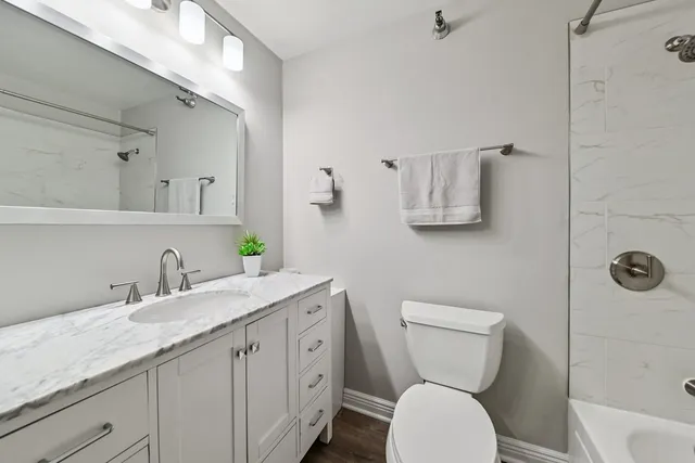 a bathroom with a granite countertop toilet sink and mirror