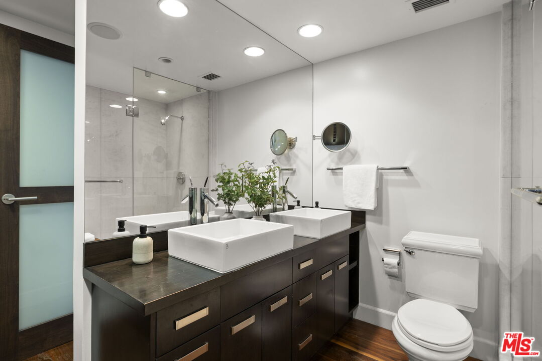 2222 Avenue Of The Stars, Unit 1004 Los Angeles, CA 90067 - Photo 12 of 25 a bathroom with a granite countertop sink a toilet a mirror and shower