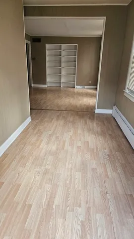 a view of empty room with wooden floor and fan