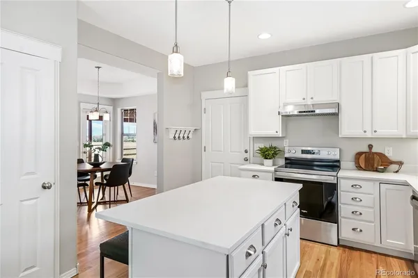 a kitchen a white cabinets and chairs
