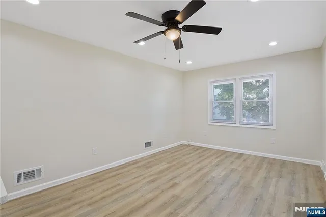 an empty room with a window and a fan
