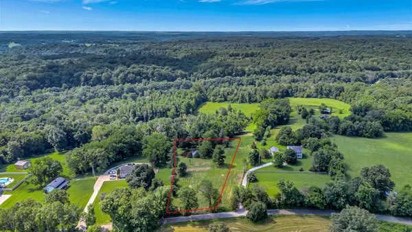 an aerial view of residential houses with outdoor space and trees